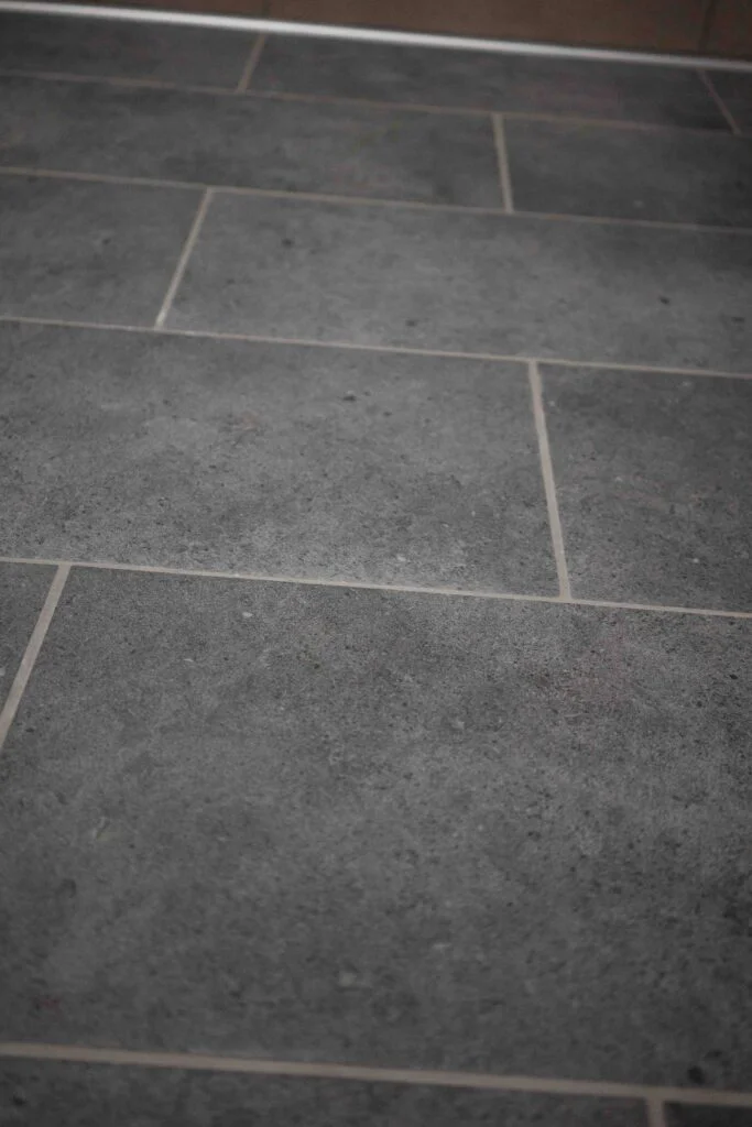 Close-up of gray porcelain floor tile and grout lines in a finished restroom