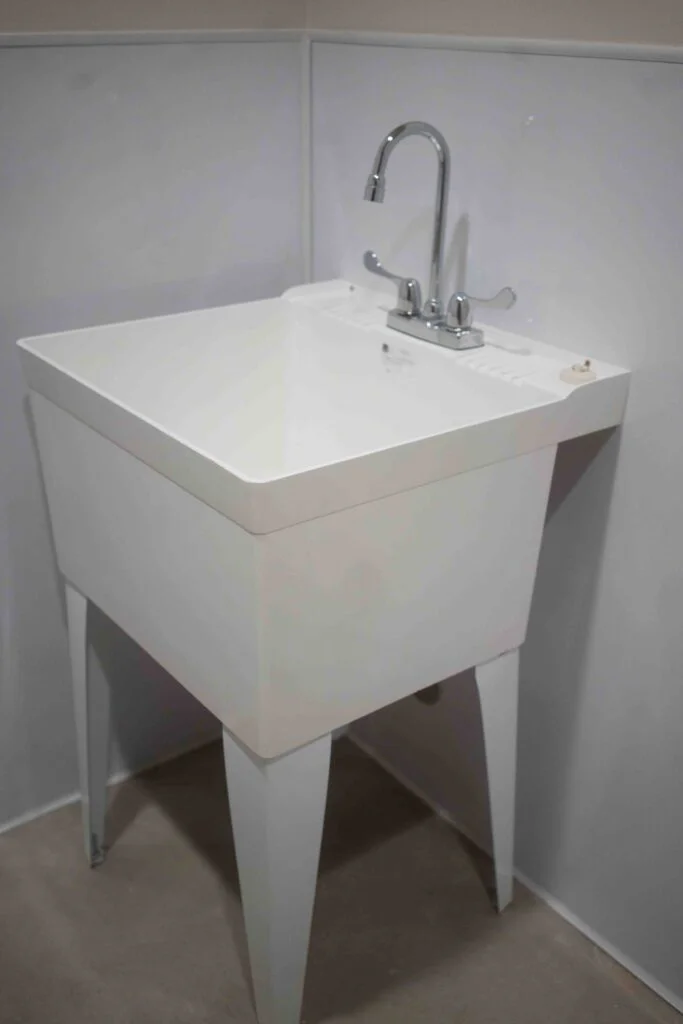 White utility sink with a gooseneck faucet installed in a service room