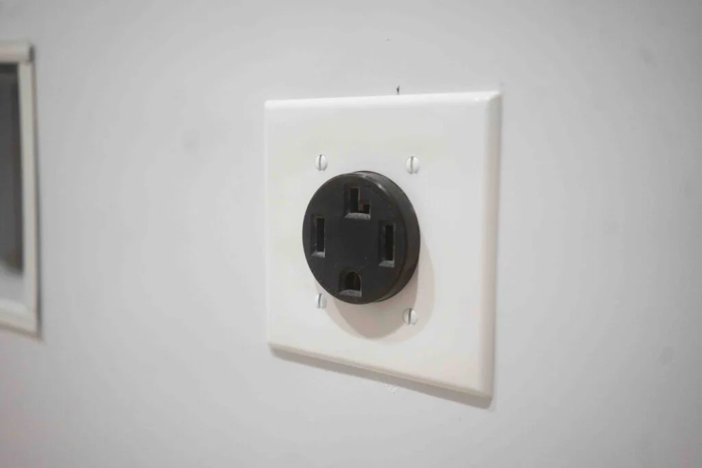 Close-up of a black 240-volt dryer outlet mounted on a white wall