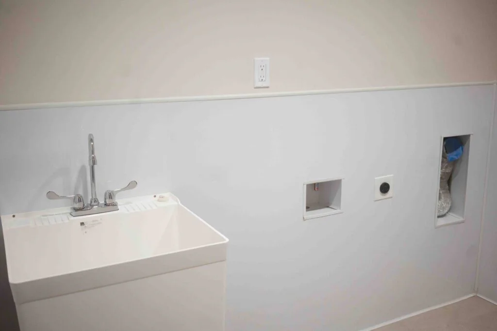 Laundry room wall showing a sink, dryer vent, and washer and dryer hookups