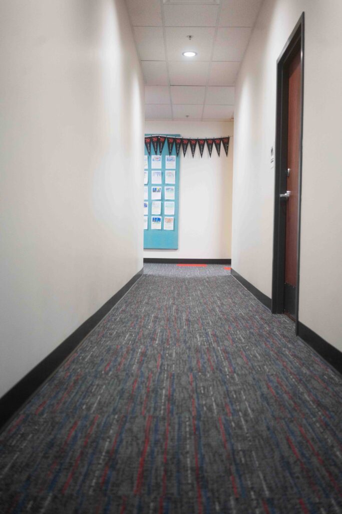 Hallway with red floor markings leading toward a decorated classroom entrance