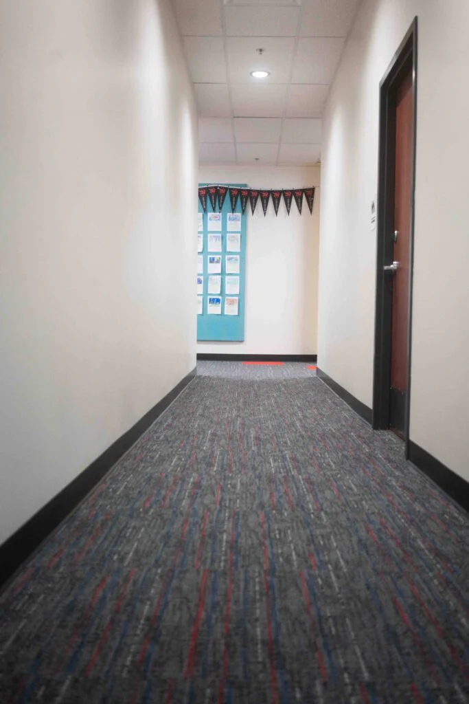 Hallway with red floor markings leading toward a decorated classroom entrance
