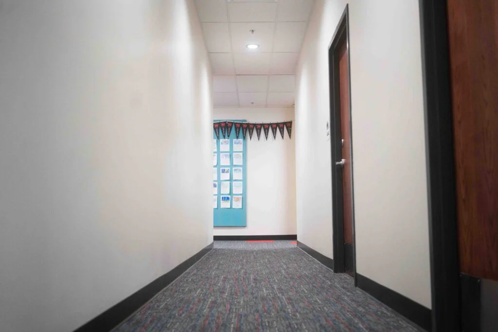 School hallway with an open door revealing a classroom bulletin board display