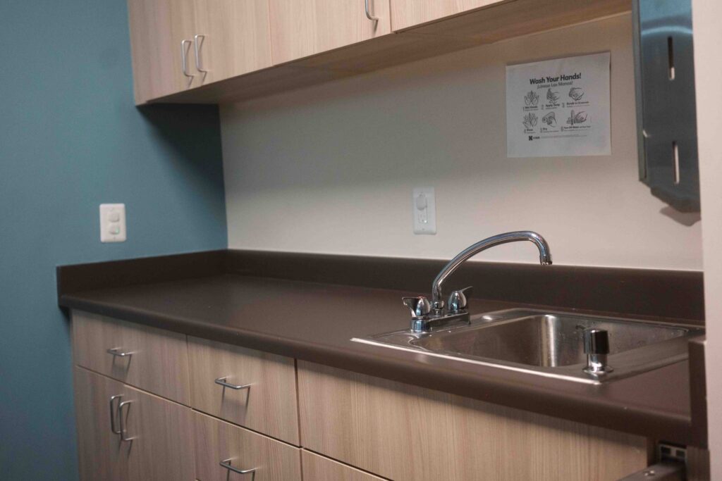 Classroom sink with a wash-your-hands sign and stainless towel dispenser