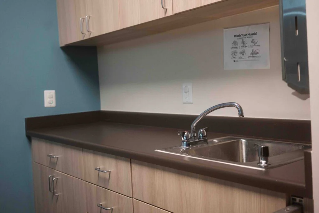 Classroom sink with a wash-your-hands sign and stainless towel dispenser