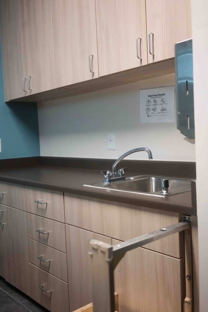 Close-up of a classroom sink faucet, countertop, and cabinet hardware