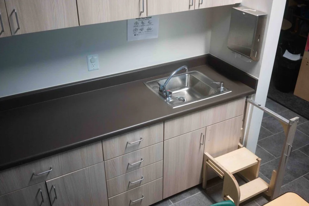 Classroom sink and cabinets with a wooden step stool for young students
