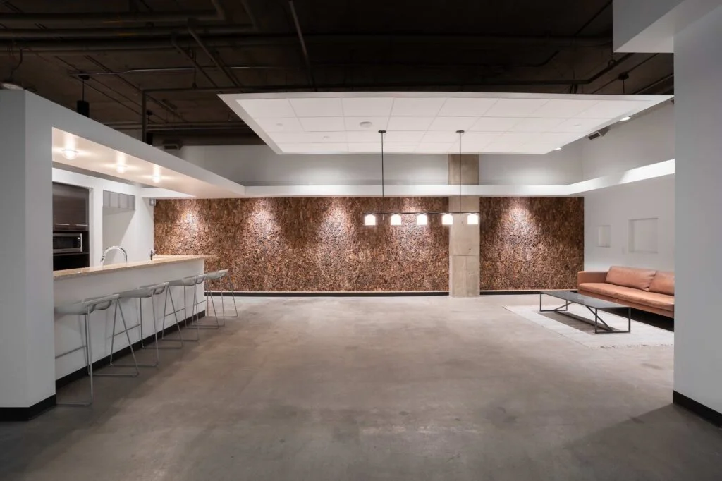 Open lounge area with a cork accent wall, bar seating and a leather sofa