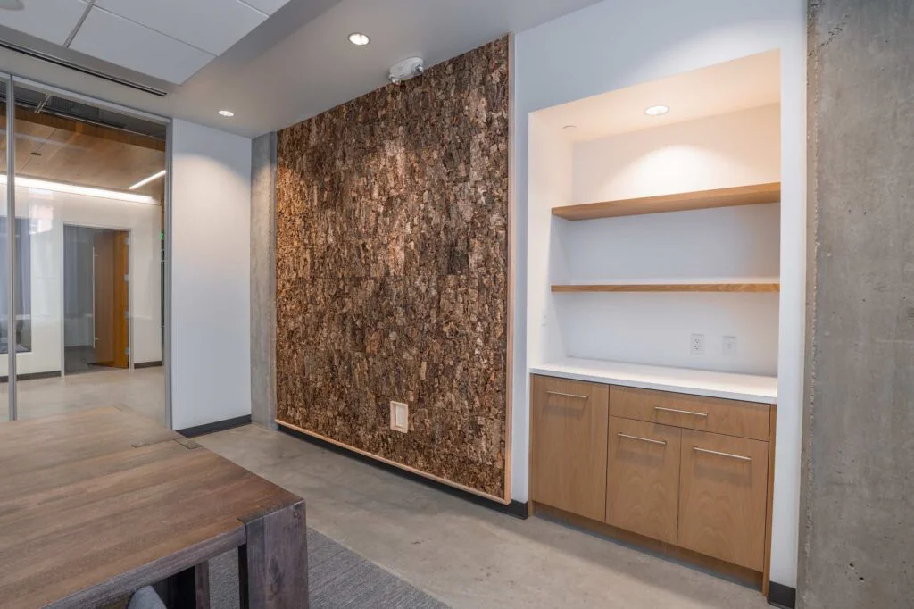 Cork accent wall beside a built-in wood shelving nook near a glass office door
