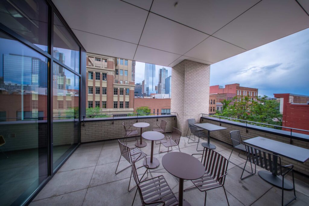 Outdoor office terrace with round metal cafe tables and chairs overlooking the downtown skyline