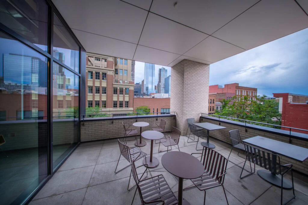 Outdoor office terrace with round metal cafe tables and chairs overlooking the downtown skyline