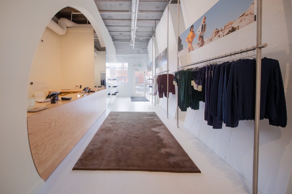 Plywood checkout counter and clothing racks beneath a desert mural near the store entrance