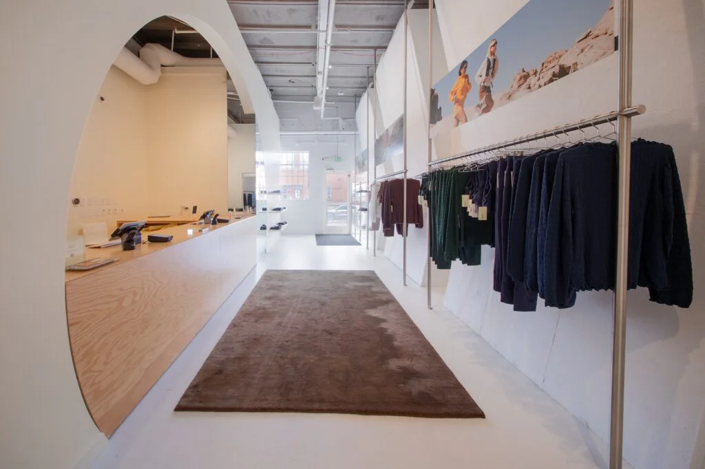 Plywood checkout counter and clothing racks beneath a desert mural near the store entrance