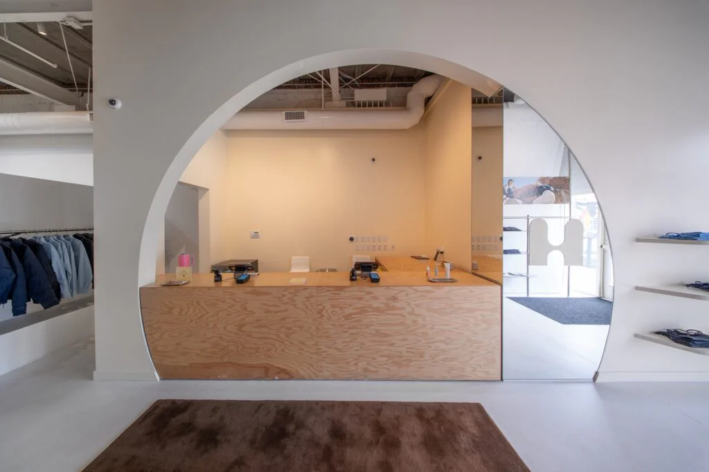 Curved plywood checkout counter framed by an arched mirrored alcove in a retail store