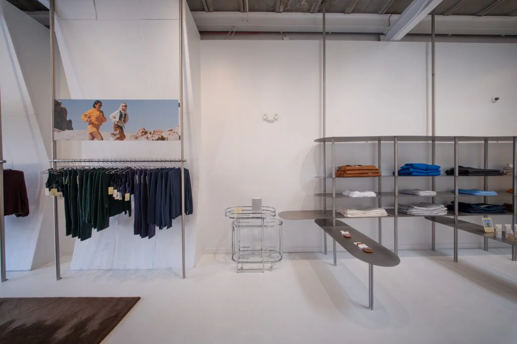 Hanging apparel rack beneath a desert hiking photo mural next to folded clothing shelves