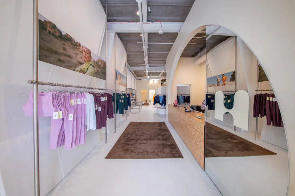Pink and maroon activewear hanging on a display rack beneath a mountain photo mural