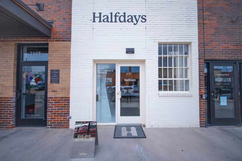 Exterior storefront of a white brick retail building with Halfdays signage and glass entry door