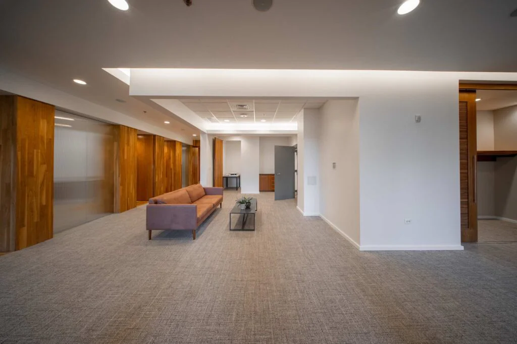 Modern office lobby with a leather sofa, coffee table, and warm wood-paneled walls