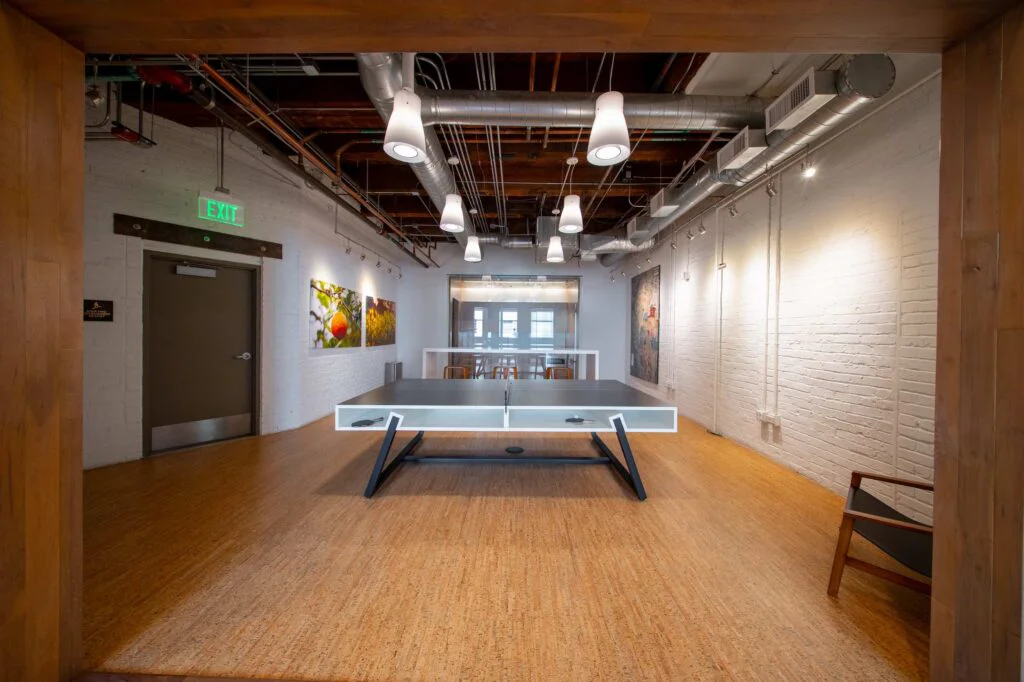 Recreation room with a ping pong table, framed nature photography on brick walls, and bar seating beyond