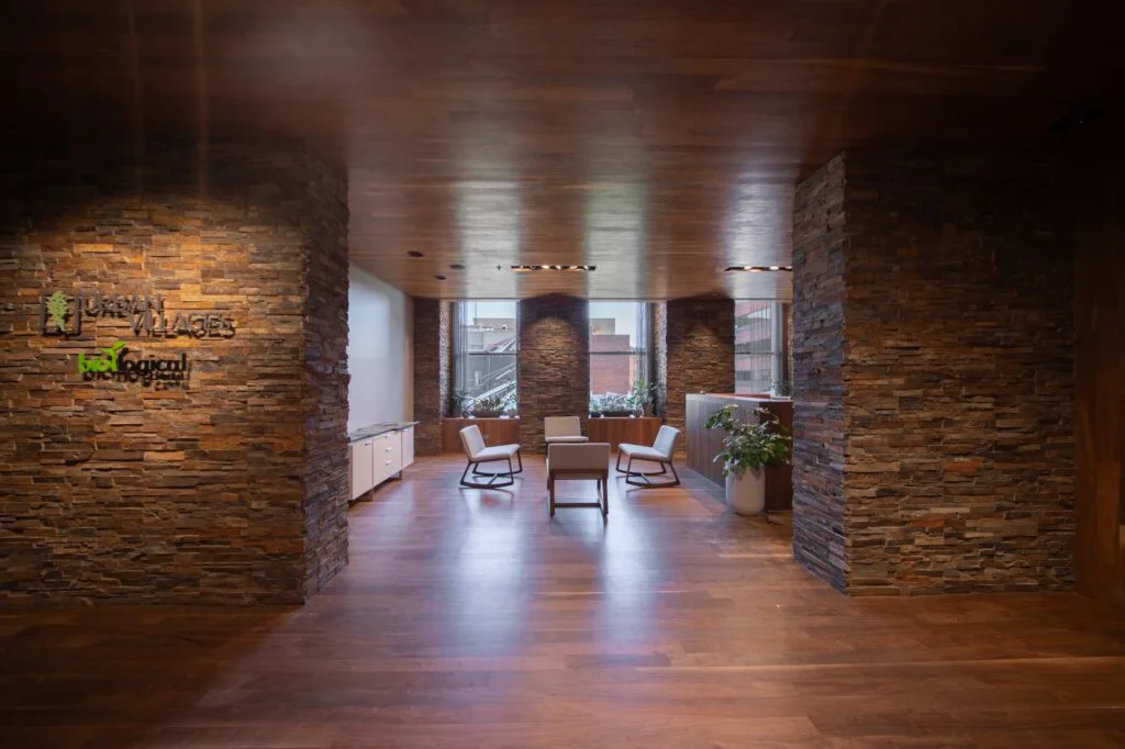 Office reception area featuring a stacked stone accent wall, wood plank ceiling, and modern rocking lounge chairs