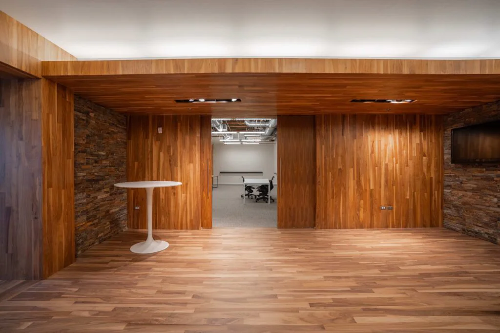 Wood-clad break area with a round pedestal table and sliding doors opening to a conference room