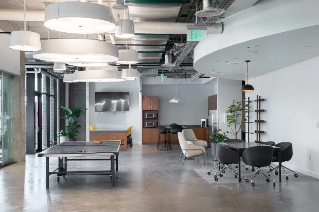 Office break area with a ping pong table, lounge chairs, and a kitchenette with stainless appliances