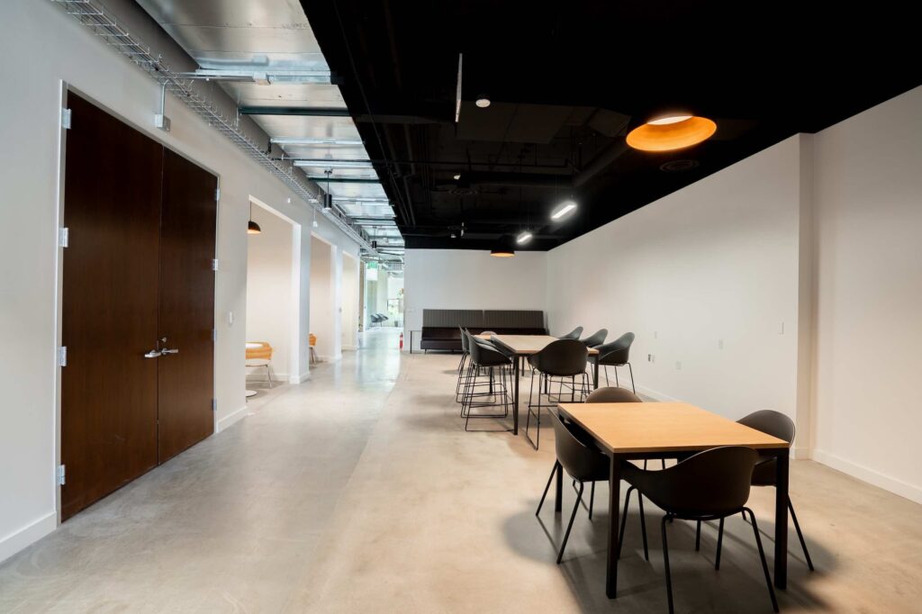 Office corridor with a dark wood door, seating alcoves, and booth-style bench seating