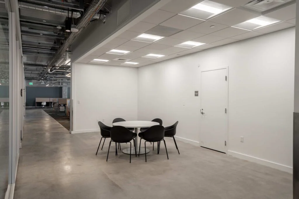 Round meeting table with black chairs in an open office breakout area