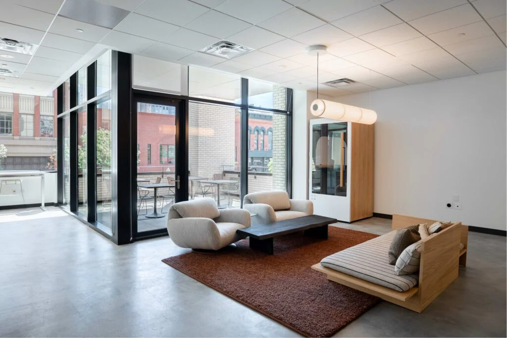 Lounge seating with floor-to-ceiling windows overlooking an outdoor patio and city buildings