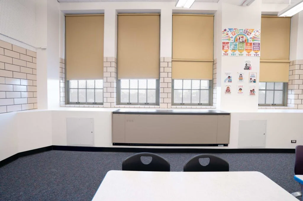 Classroom windows with tan roller shades, tile wainscot, and motivational posters