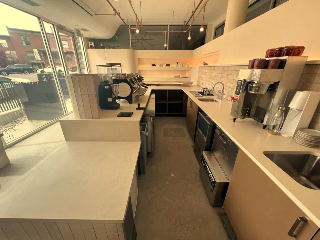 Coffee shop counter and copper pipe lighting with floor-to-ceiling windows overlooking the street
