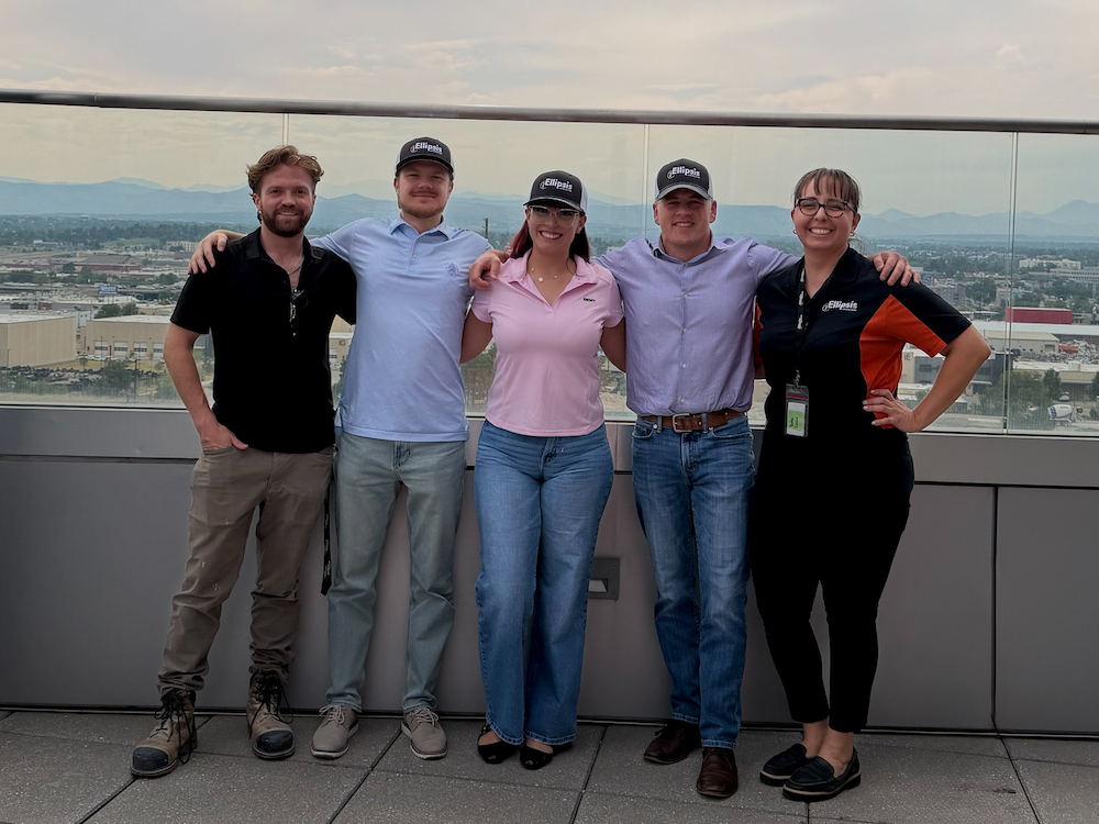 Ellipsis Construction team members posing together on a rooftop terrace with a city skyline in the background