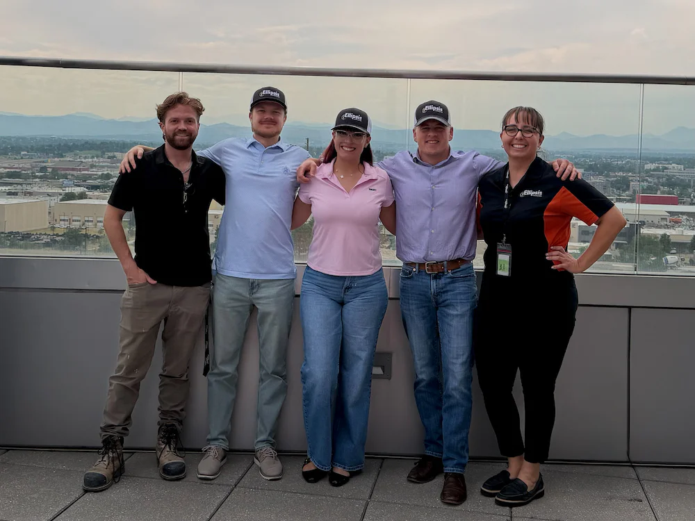 Ellipsis Construction team members posing together on a rooftop terrace with a city skyline in the background